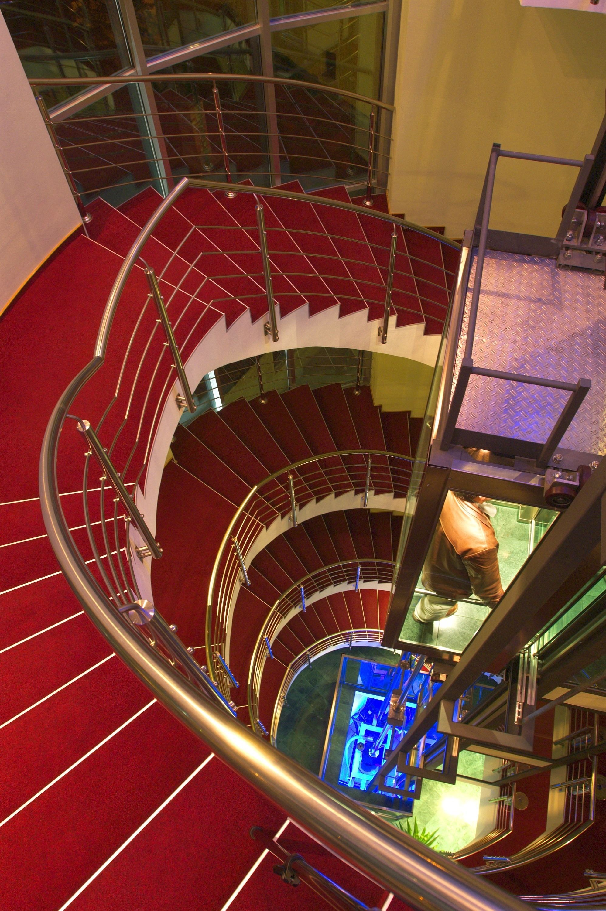 A spiral staircase with red carpeted steps and metal railings.