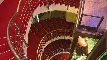 A spiral staircase with red carpeted steps and metal railings.