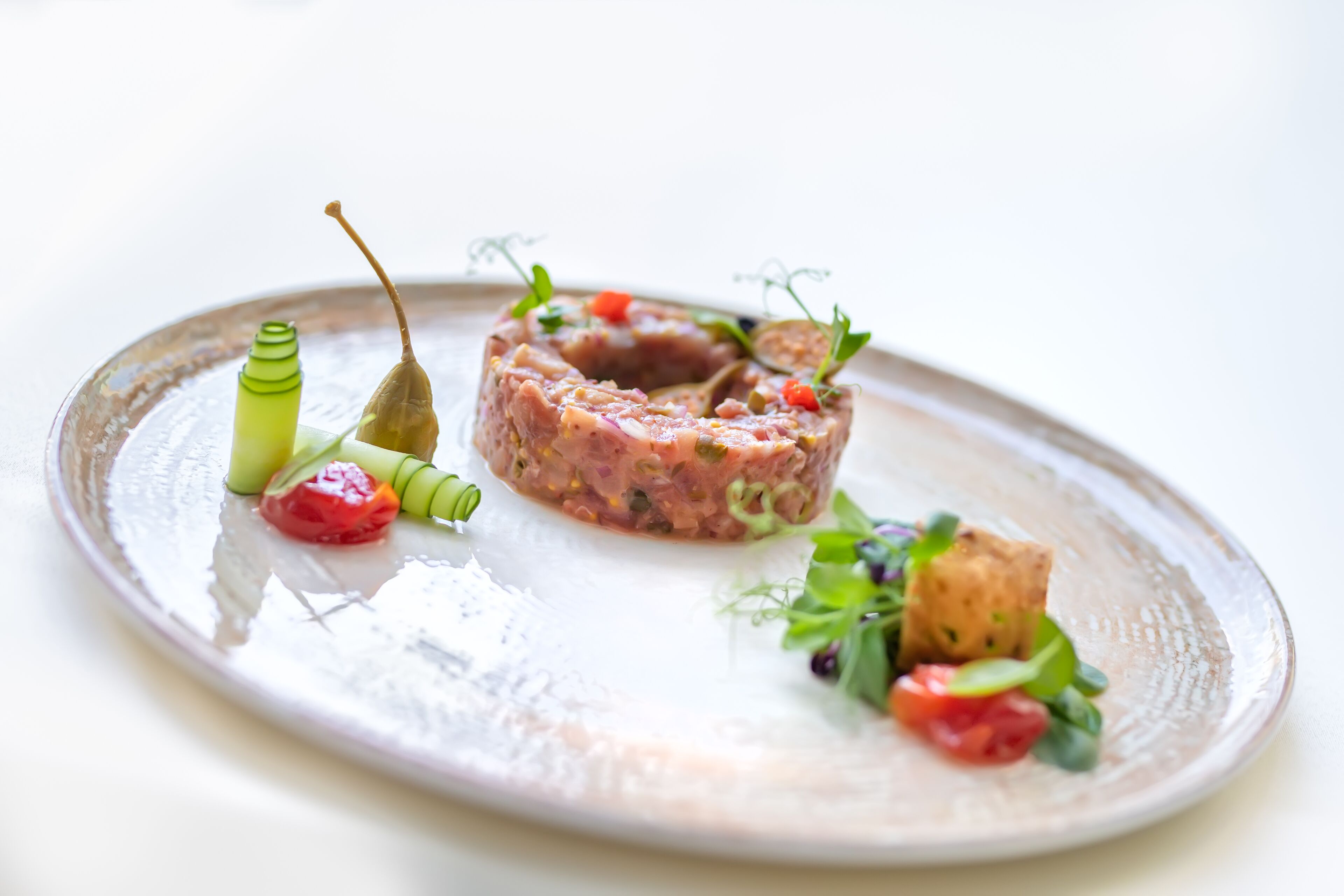 Ein Teller mit einem Gericht aus Fleisch, garniert mit Gemüse und Kräutern.