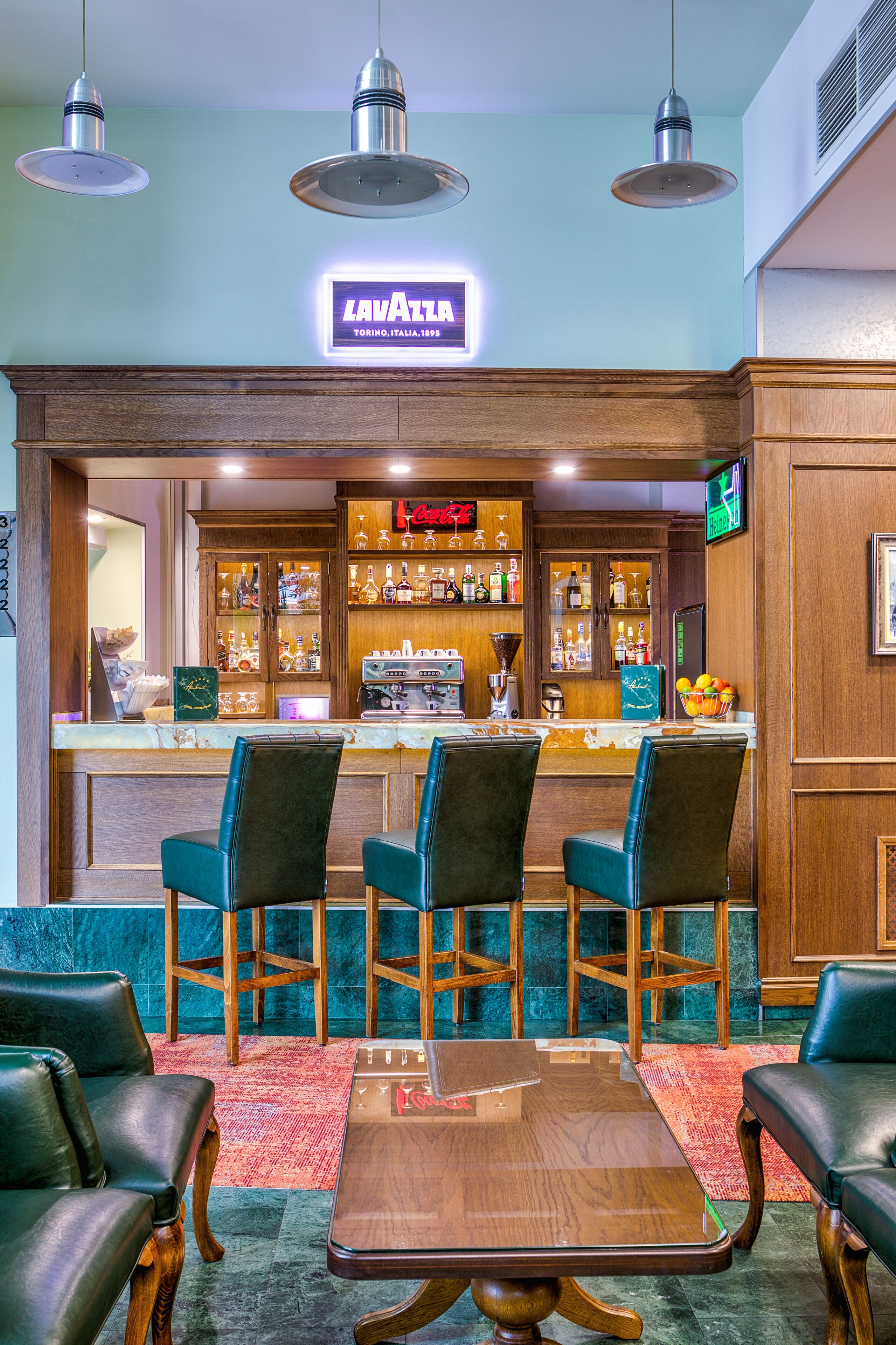 Zona de bar con mostrador de madera, taburetes y una pantalla de televisión.