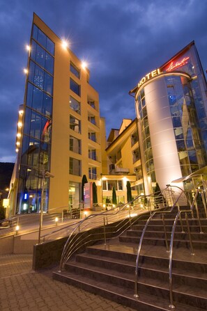 Un hotel moderno con fachada de vidrio, un llamativo letrero que dice 
