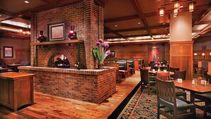 A restaurant with a brick fireplace, wooden tables, and booths.