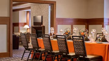 A dining area with a long table, multiple chairs, and a television in the background.