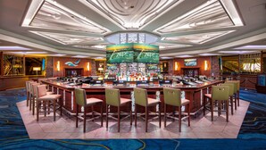 A bar area with a central bar, multiple seating arrangements, and a ceiling with unique lighting fixtures.