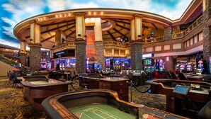 A casino with multiple blackjack tables, a craps table, and a sportsbook area.
