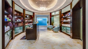 A spacious lobby with a central reception desk, glass display cases, and a chandelier.