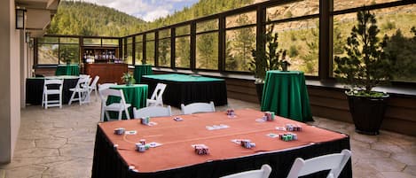 An outdoor patio with tables set for a game, surrounded by a scenic mountain view.