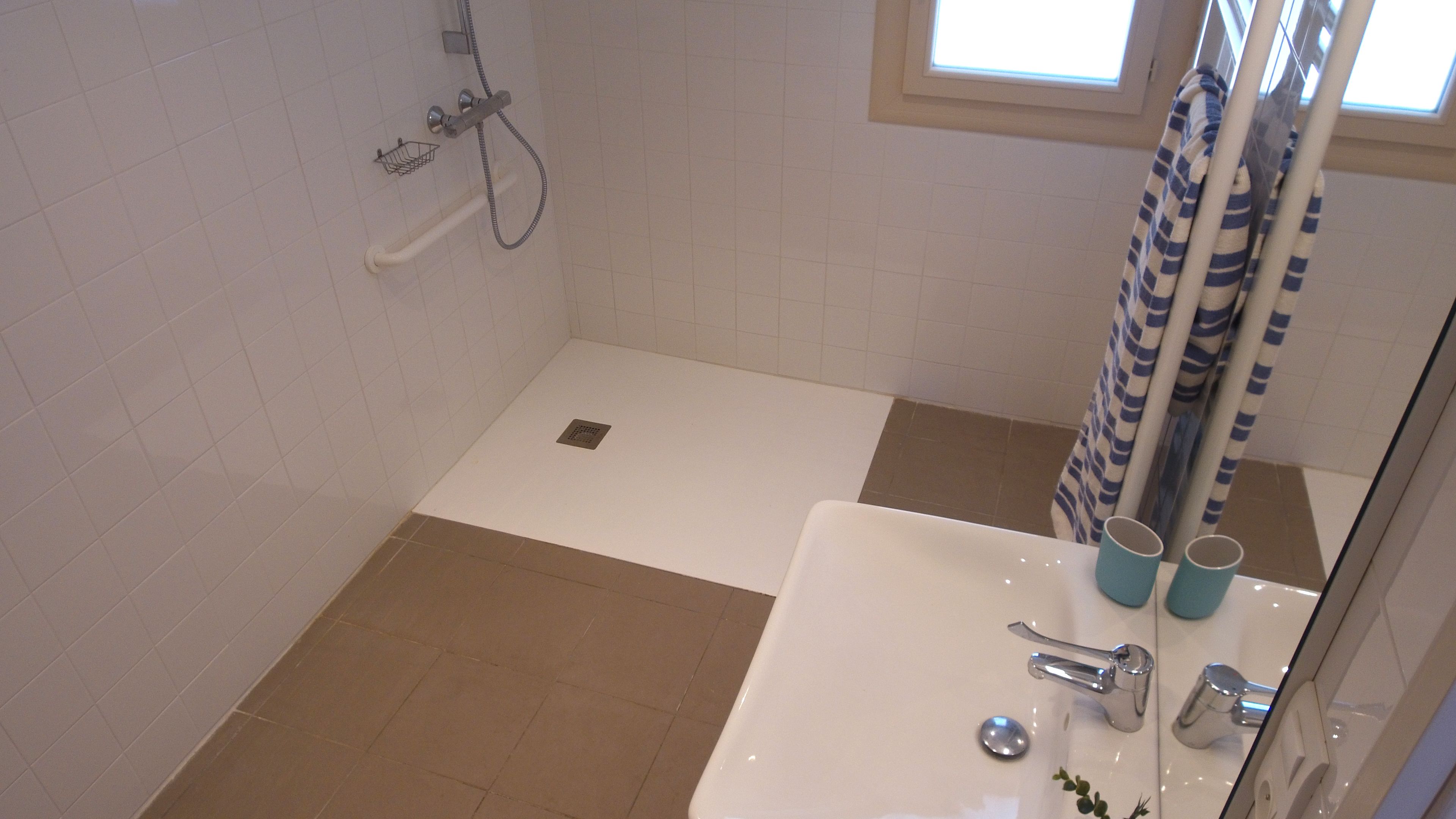 A bathroom with a shower, a sink, and a window.