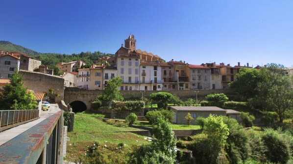 Un pueblo histórico con una iglesia destacada, un puente de piedra y abundante vegetación.