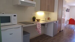 Una cocina compacta equipada con microondas, lavavajillas y fregadero.