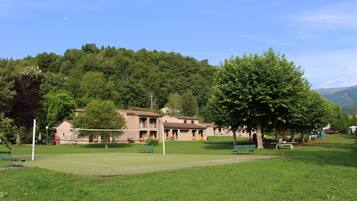 Un parc doté d’un court de tennis, de tables de pique-nique et d’un bâtiment avec plusieurs balcons.