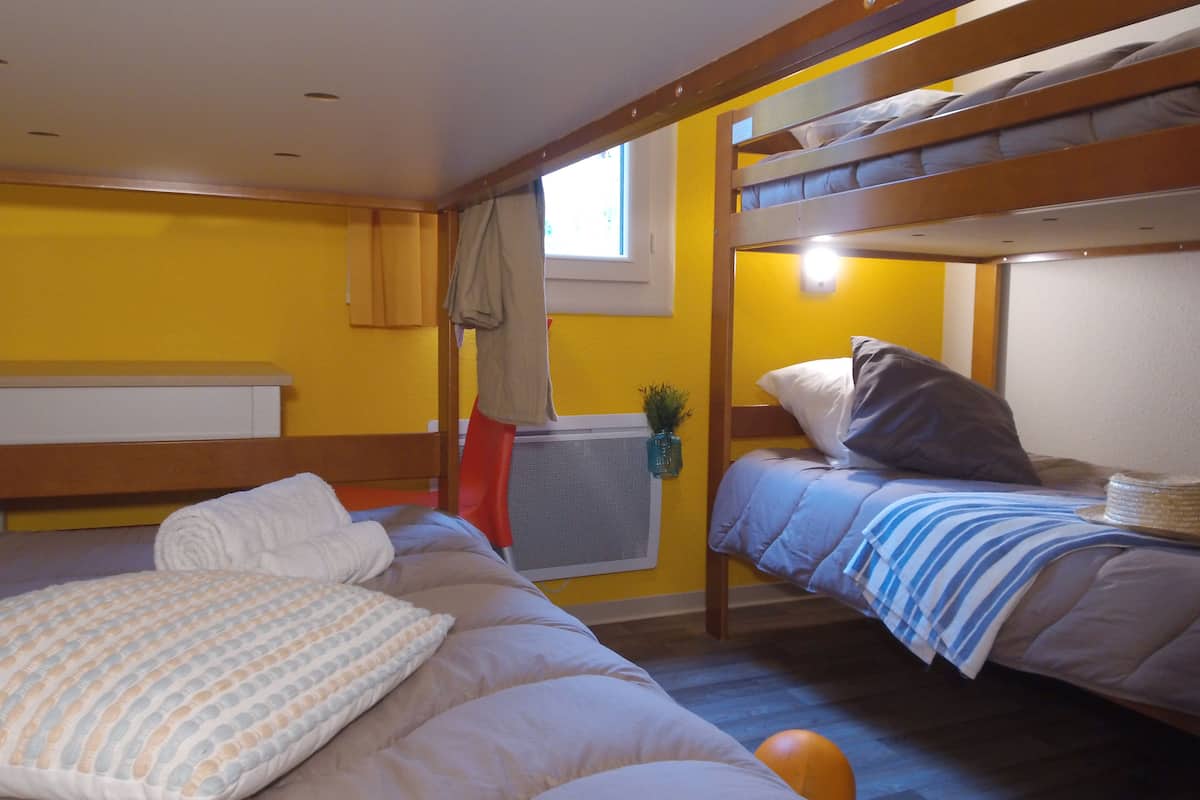 A bunk bed room with a window, a radiator, and a small plant.