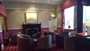 A room with a fireplace, several armchairs, a table, and a window with curtains. - Hardwicke Hall Manor Hotel (Hartlepool)