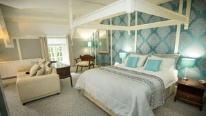 A bedroom with a canopy bed, a sitting area with a sofa, and a chair. - Hardwicke Hall Manor Hotel (Hartlepool)