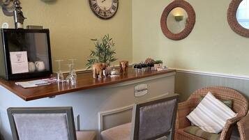A reception area with a wooden counter, a clock, a reception sign, and wicker chairs.