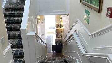 Una escalera con alfombra a cuadros que lleva a una habitación con cama y lámpara.