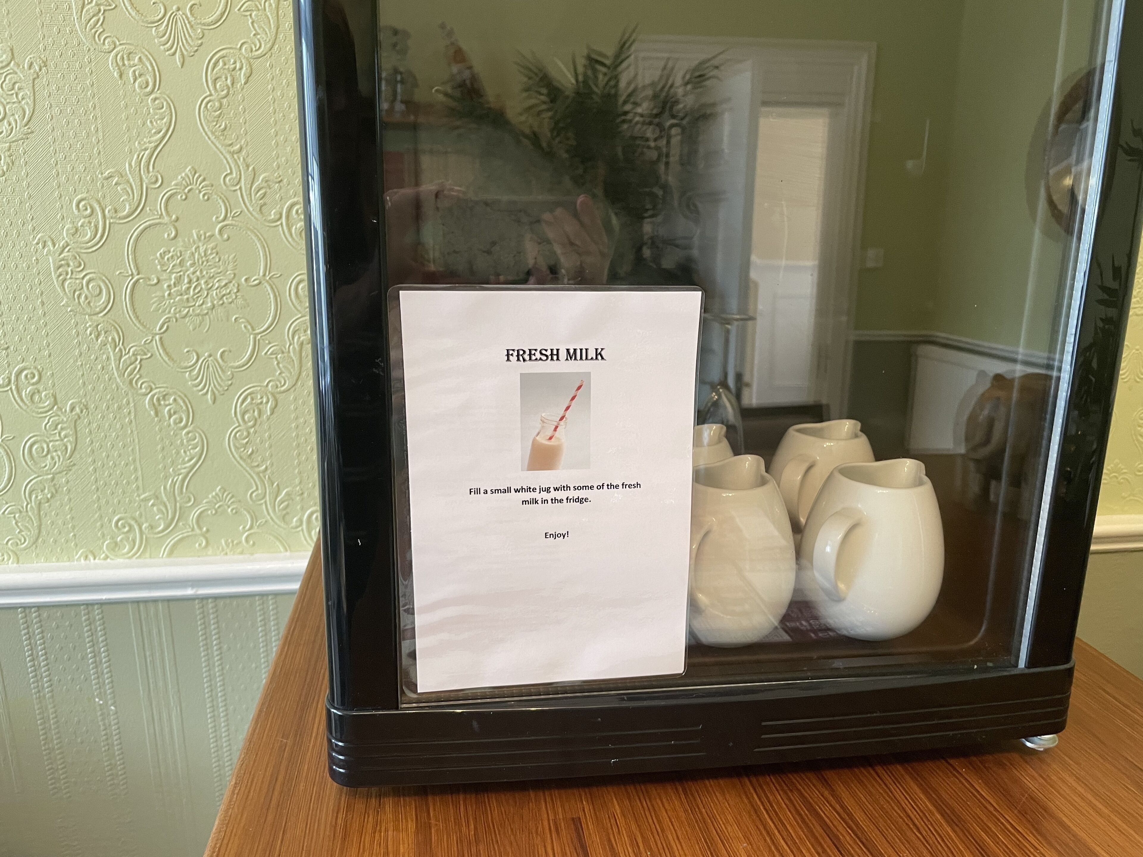 A display case with a sign instructing to fill a jug with fresh milk from the fridge.