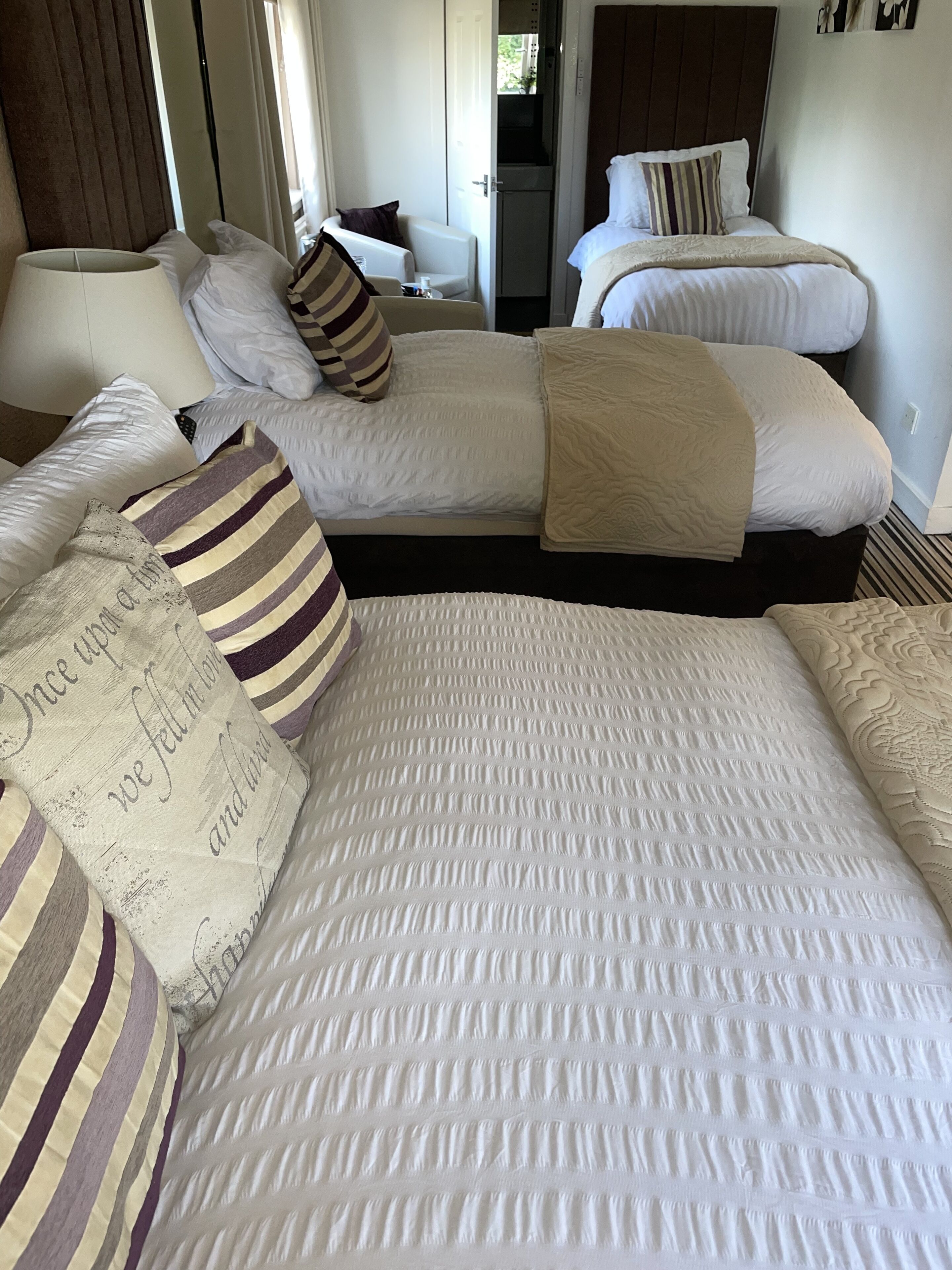A hotel room with two beds, a sofa, and a small table.