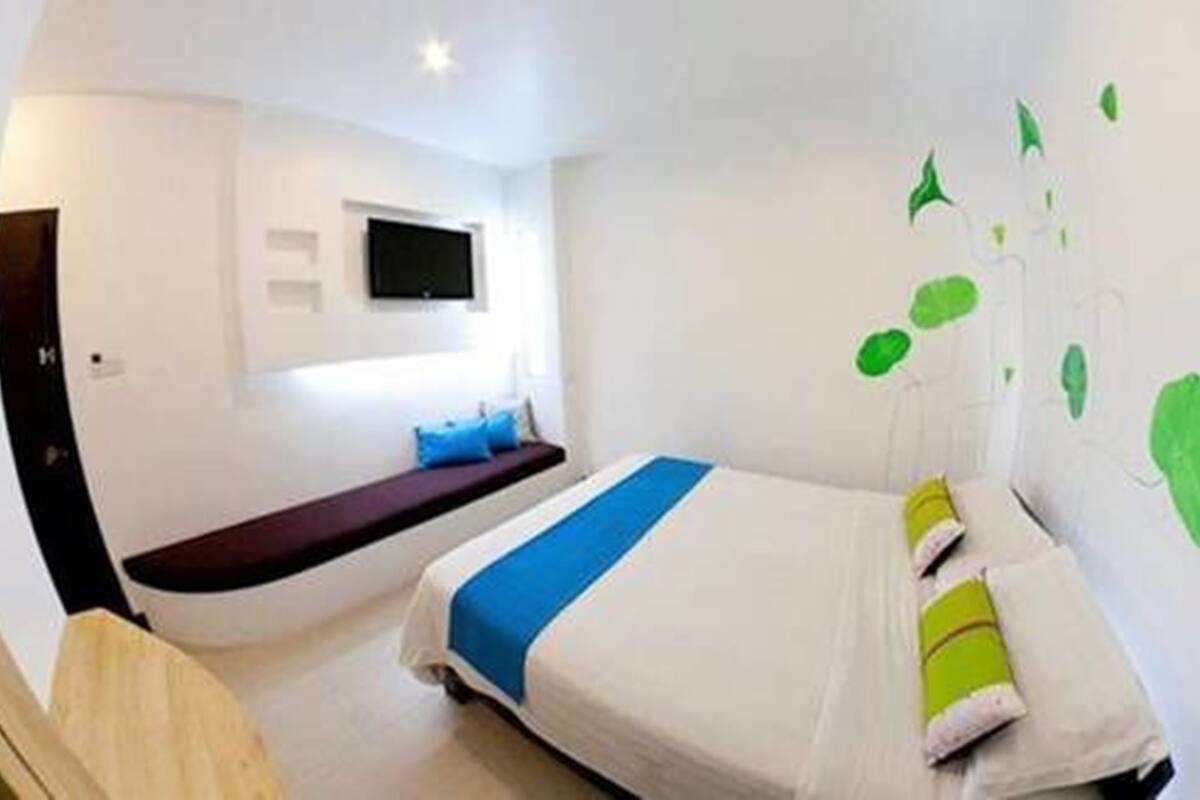 Una habitación de hotel moderna con una cama, un área de descanso y un televisor montado en la pared.