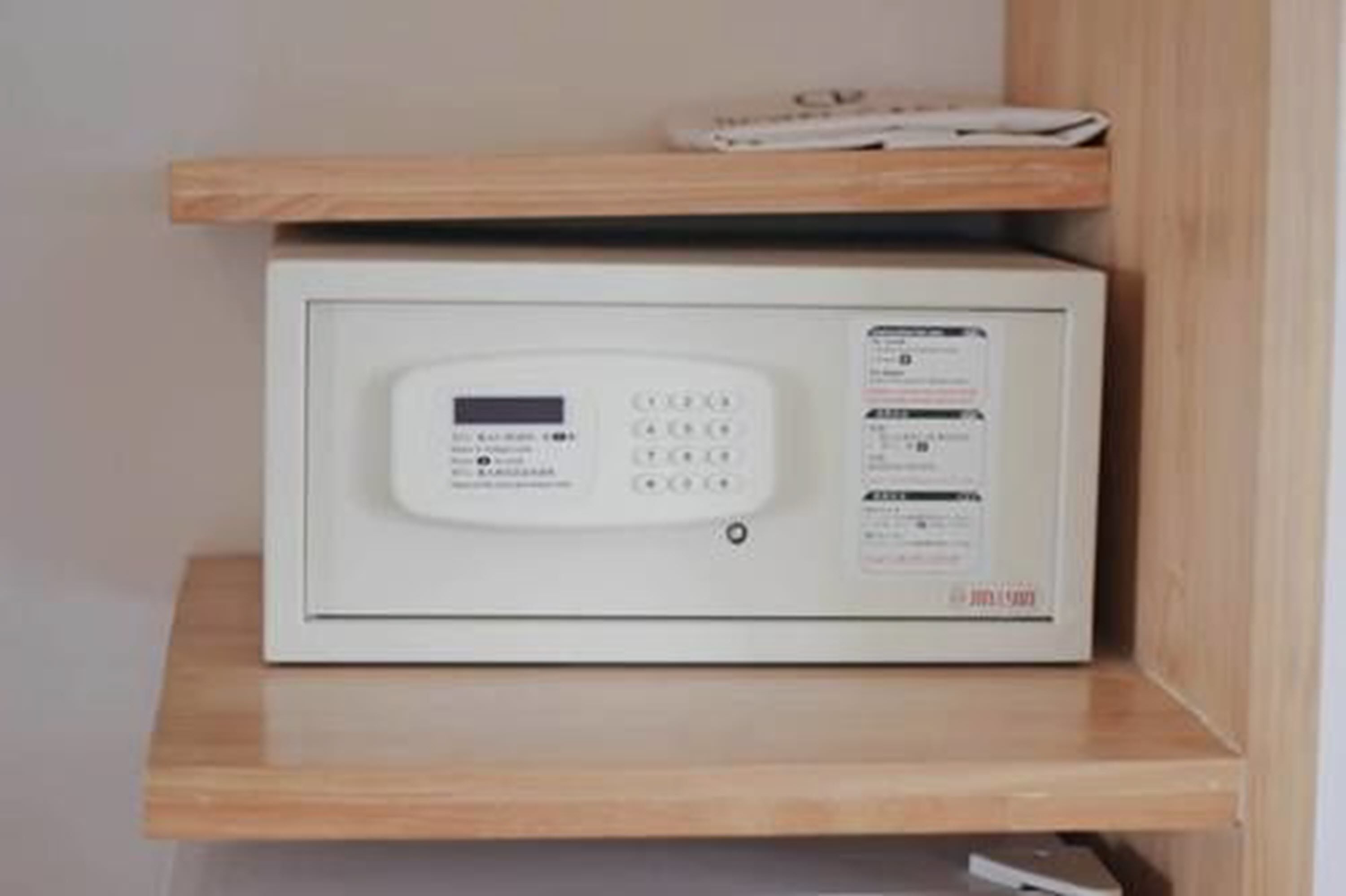 Un four à micro-ondes blanc, posé sur une étagère en bois.