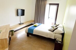 Une chambre d’hôtel avec un lit, un bureau, une télévision et une fenêtre avec des rideaux.