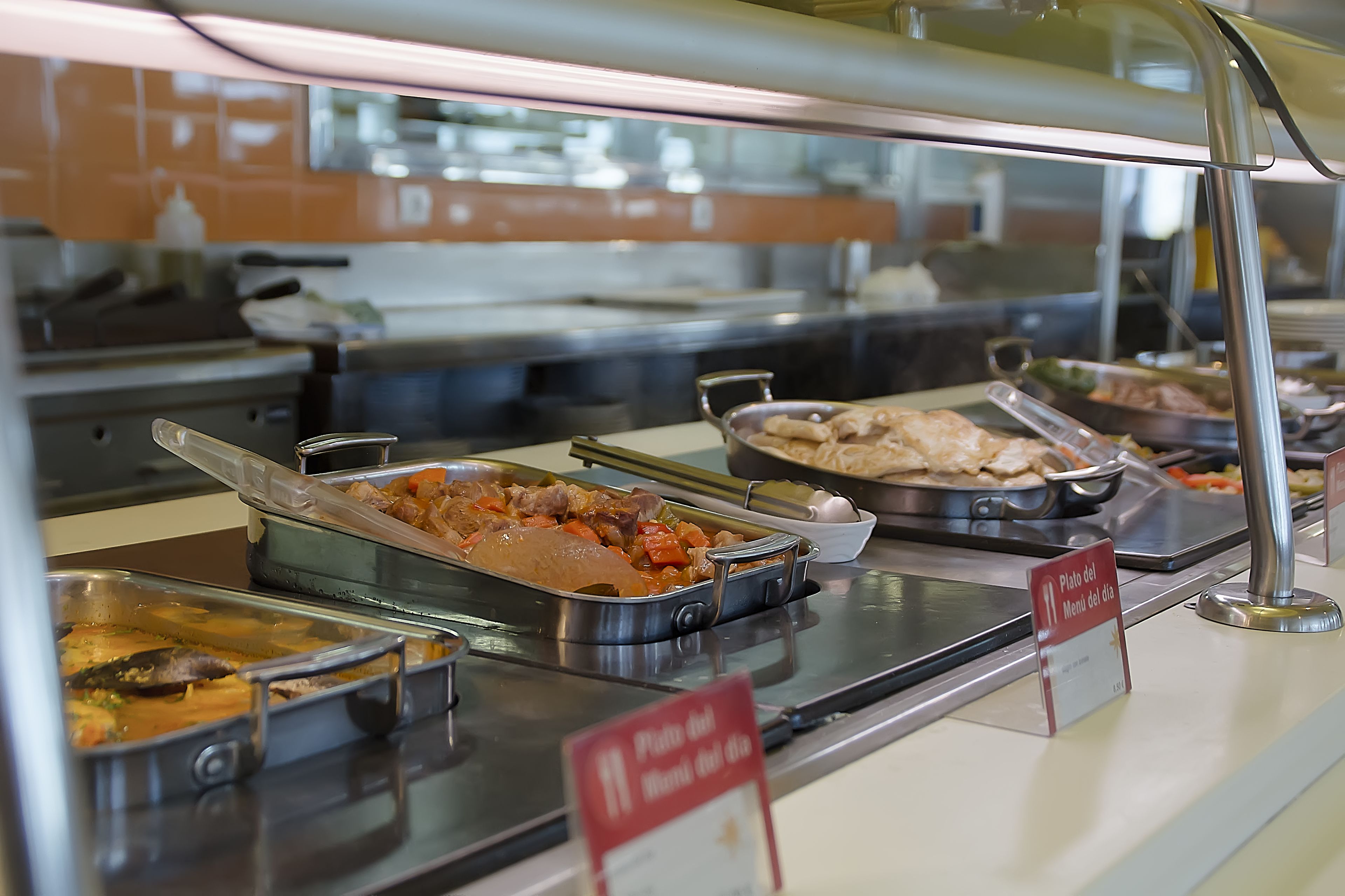 A buffet with various dishes, including a sign indicating 'Plato del Monino del dia'.