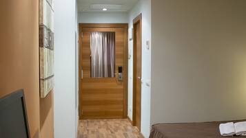 Une chambre d’hôtel avec un bureau en bois, une télévision, une télécommande et deux lits avec des serviettes.