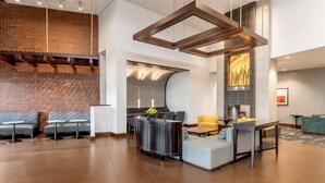 A modern lobby with a brick wall, seating area, and a fireplace. - Hyatt Place Salt Lake City Airport (Salt Lake City)