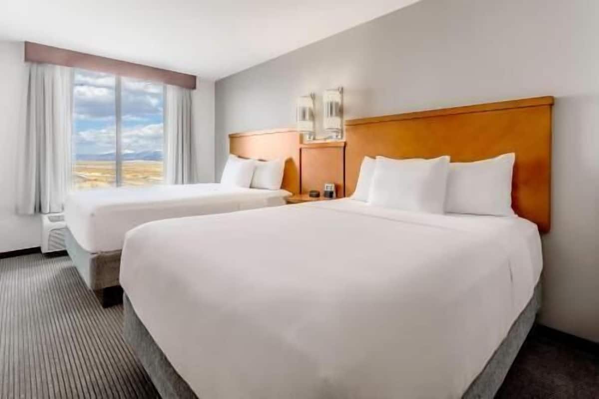 A hotel room with two beds, a large window, and a view of the landscape.