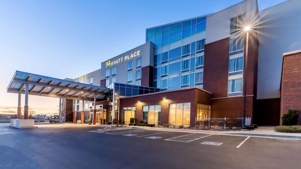 A modern hotel with a covered entrance, large windows, and a clear sky. - Hyatt Place Salt Lake City Airport (Salt Lake City)