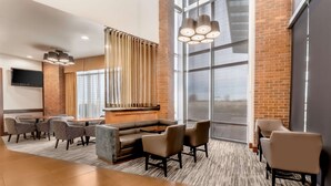 A modern hotel lobby with a seating area, a reception desk, and large windows. - Hyatt Place Salt Lake City Airport (Salt Lake City)