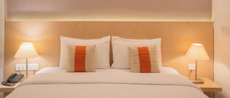 Una habitación de hotel con una cama, dos lámparas de noche, un teléfono y cuatro obras de arte enmarcadas en la pared.