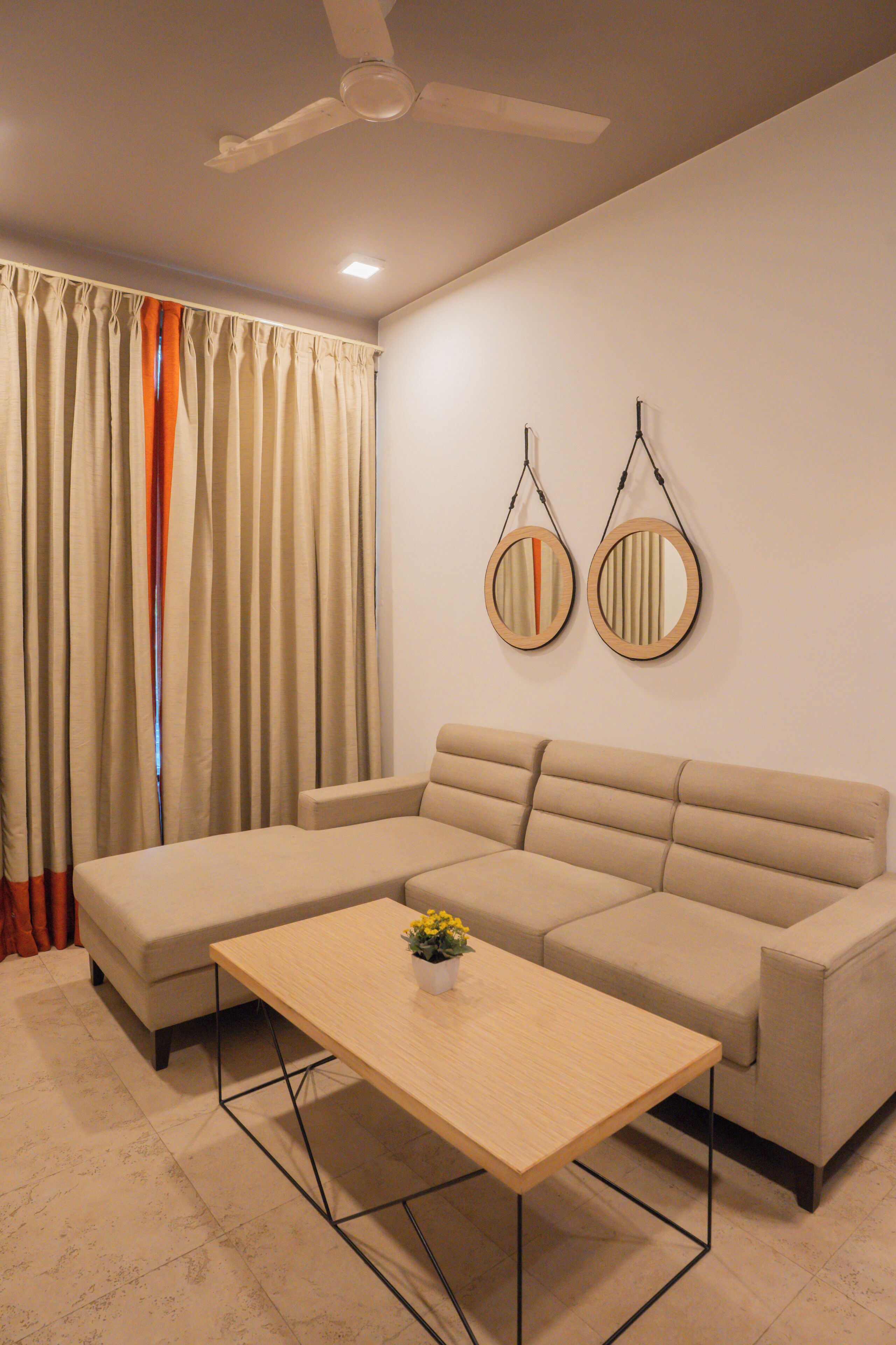 Una sala moderna con un sofá modular, una mesa de centro de madera y un ventilador de techo.