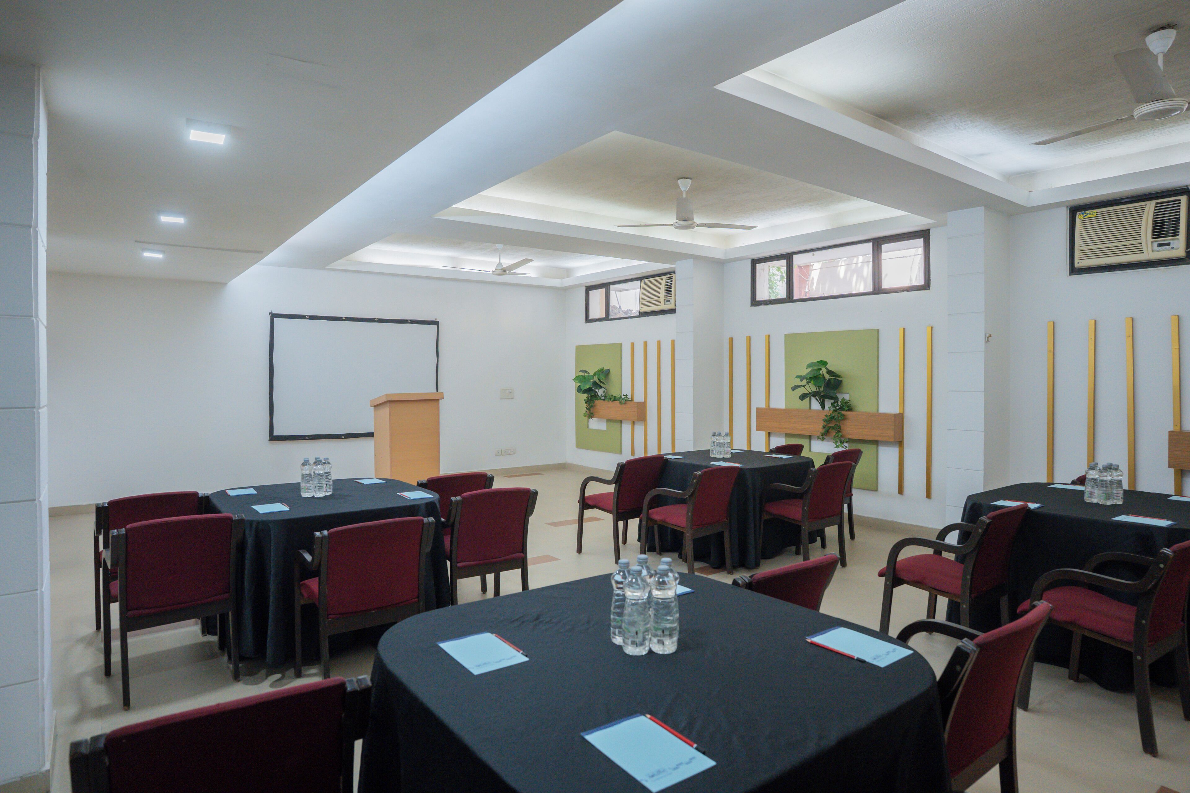 Una sala de conferencias con mesas, sillas y ventiladores de techo.