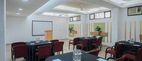 Una sala de conferencias con mesas, sillas y ventiladores de techo.