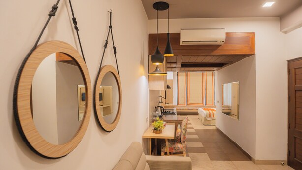 Un vestíbulo de hotel moderno con un sofá, una mesa de comedor con sillas y dos espejos grandes en la pared.
