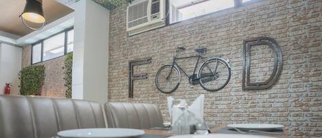 A dining area with a brick wall, a bicycle, and a table set for two.