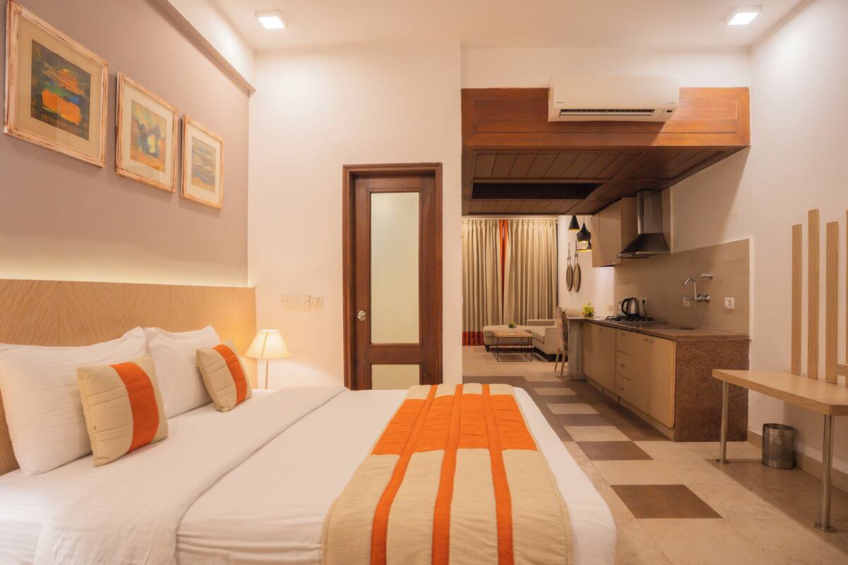 Habitación de hotel con cama, escritorio, kitchenette y baño.