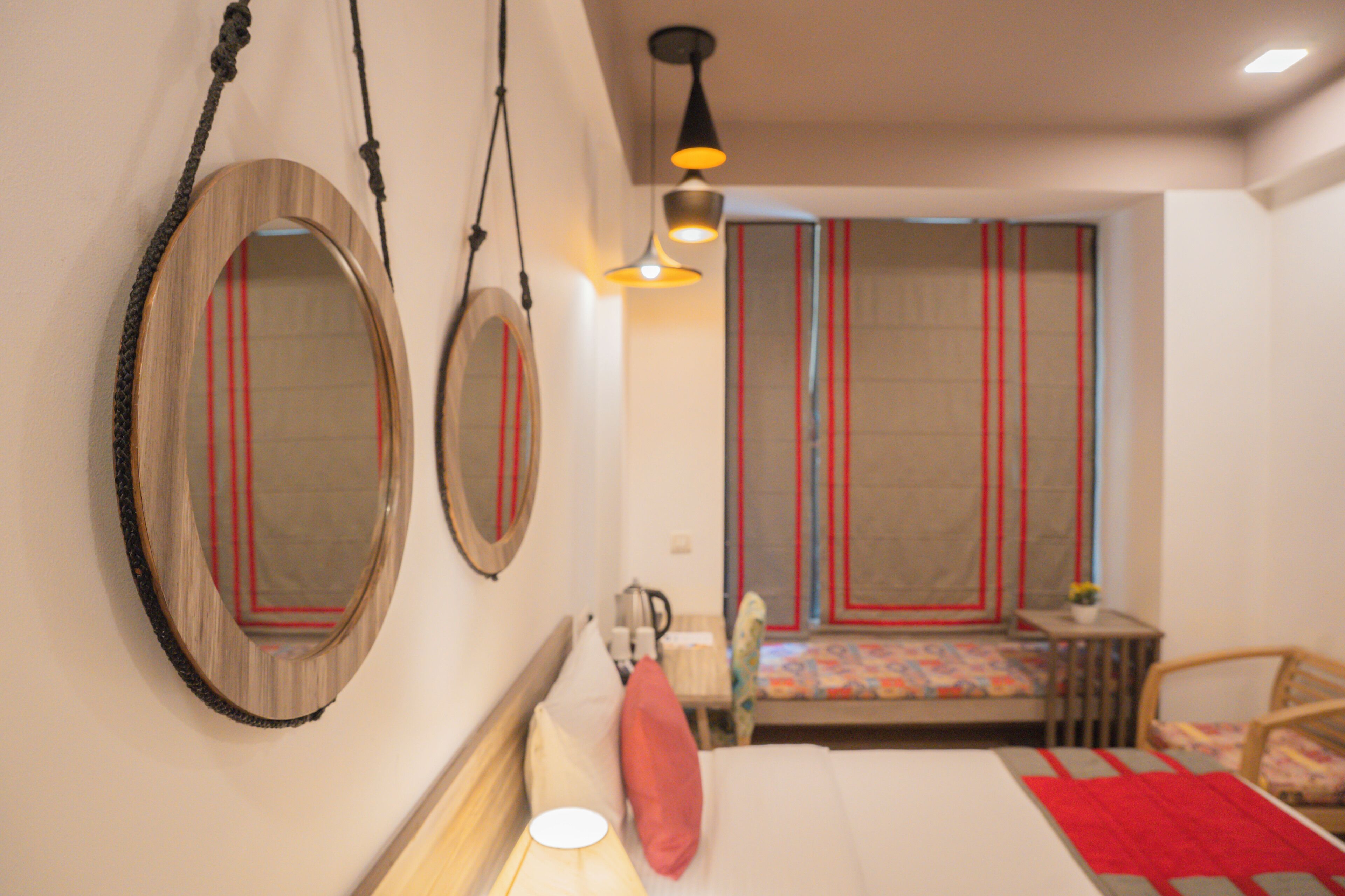 Una habitación de hotel con una cama, una mesita, una silla y dos espejos en la pared.