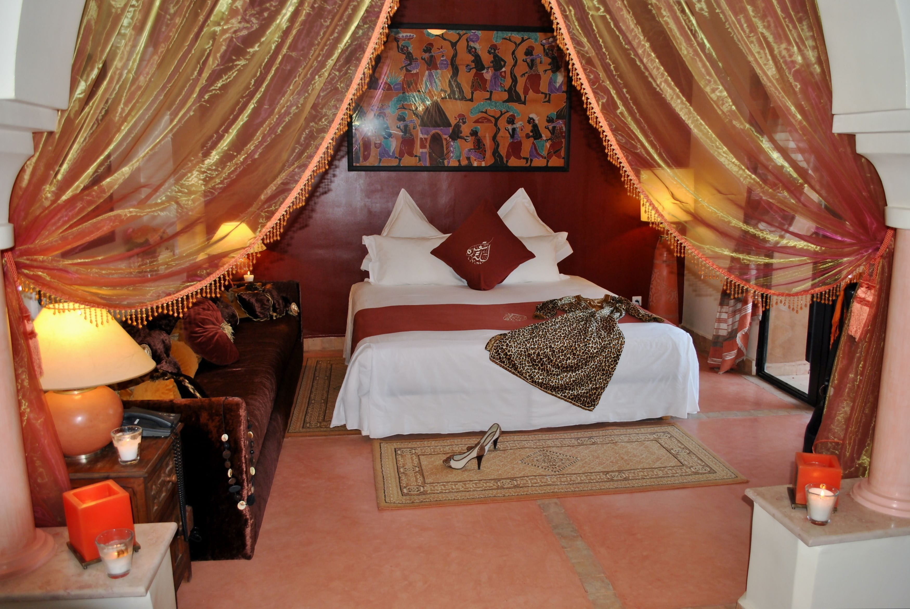 A bedroom with a bed, a nightstand, a lamp, a mirror, and a wall painting.