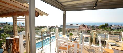 Una terraza en la azotea con piscina, zona de comedor y vistas al mar.