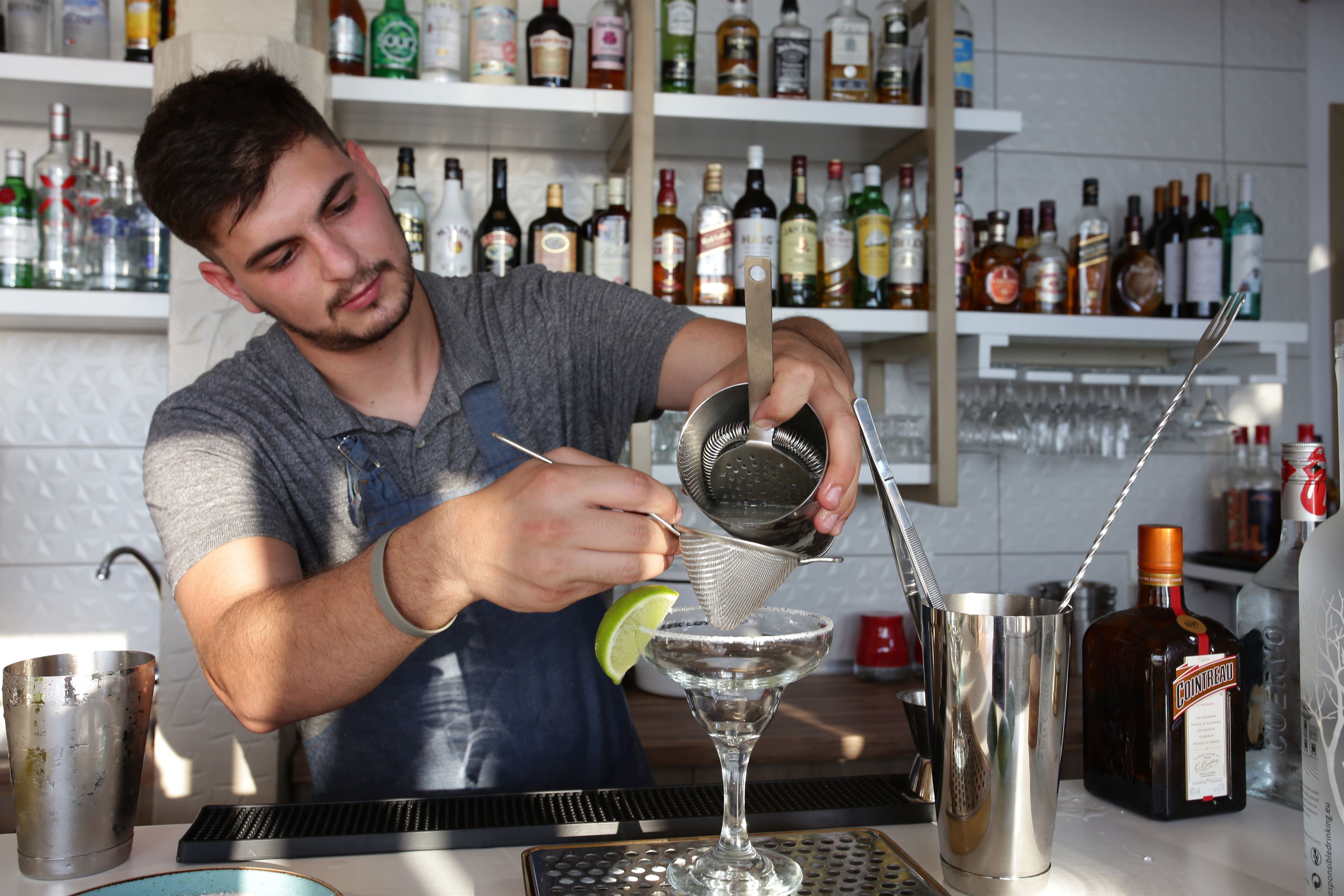 Un cantinero preparando una bebida con una rodaja de limón.