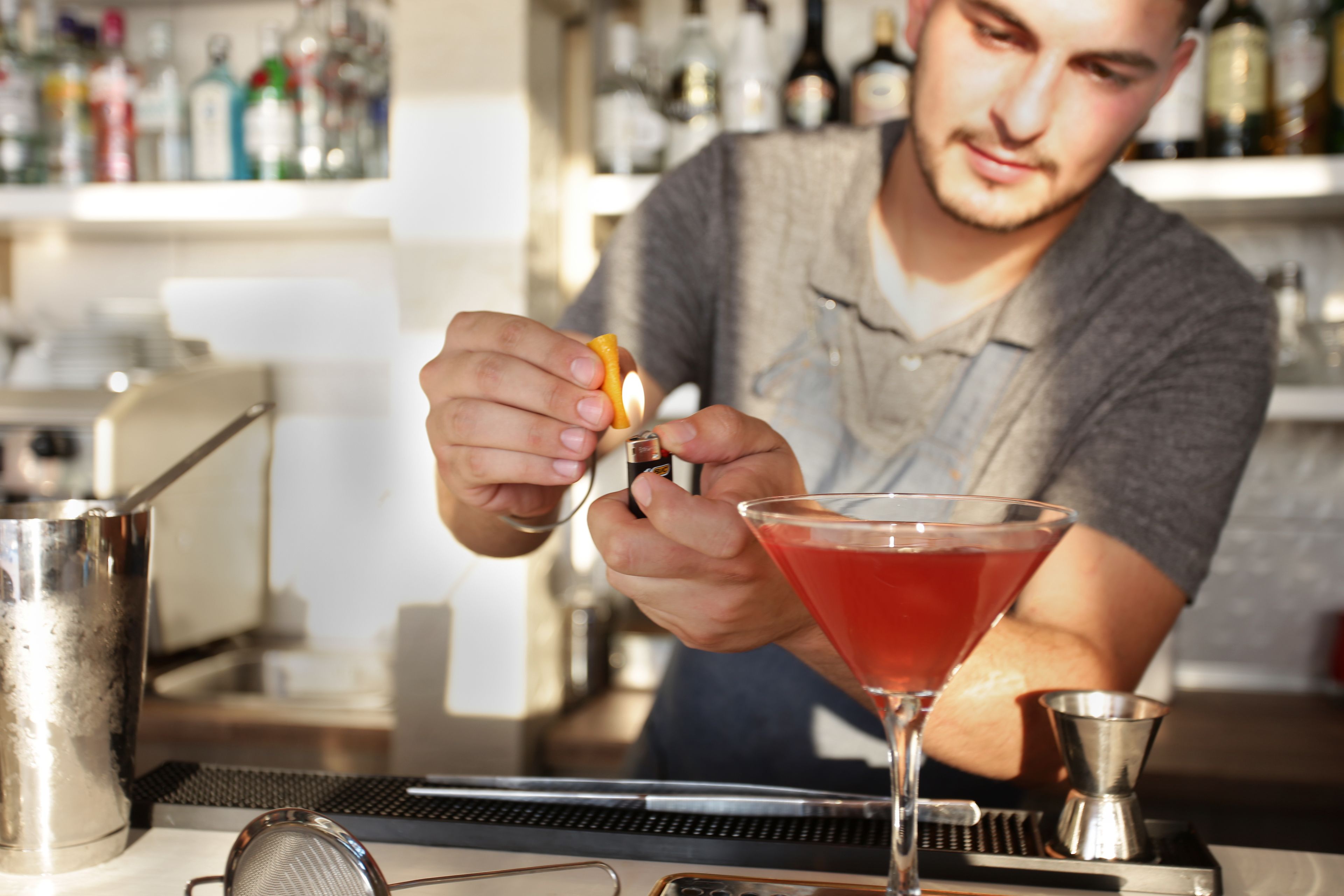 A bartender preparing a cocktail with a shaker and a martini glass on the counter.
