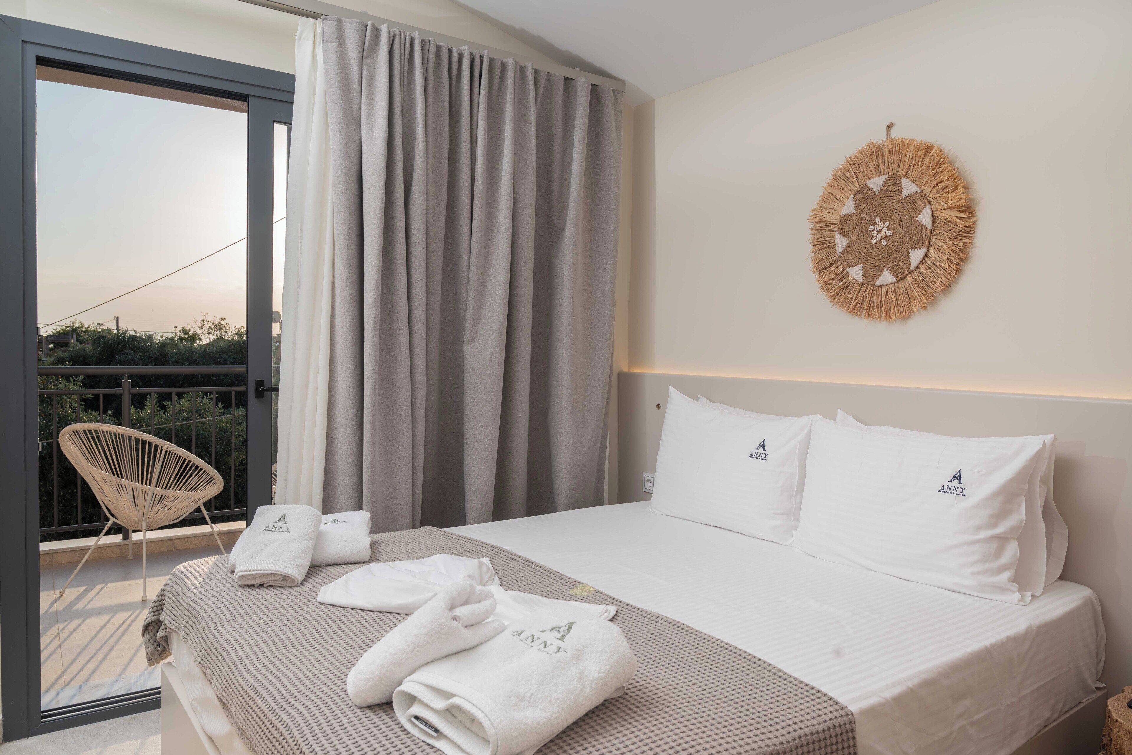 A hotel room with a bed, a balcony with a chair, and a decorative wall hanging.