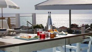 A dining table with food and drinks, overlooking a body of water. - Anny Residences & Suites (Thasos)