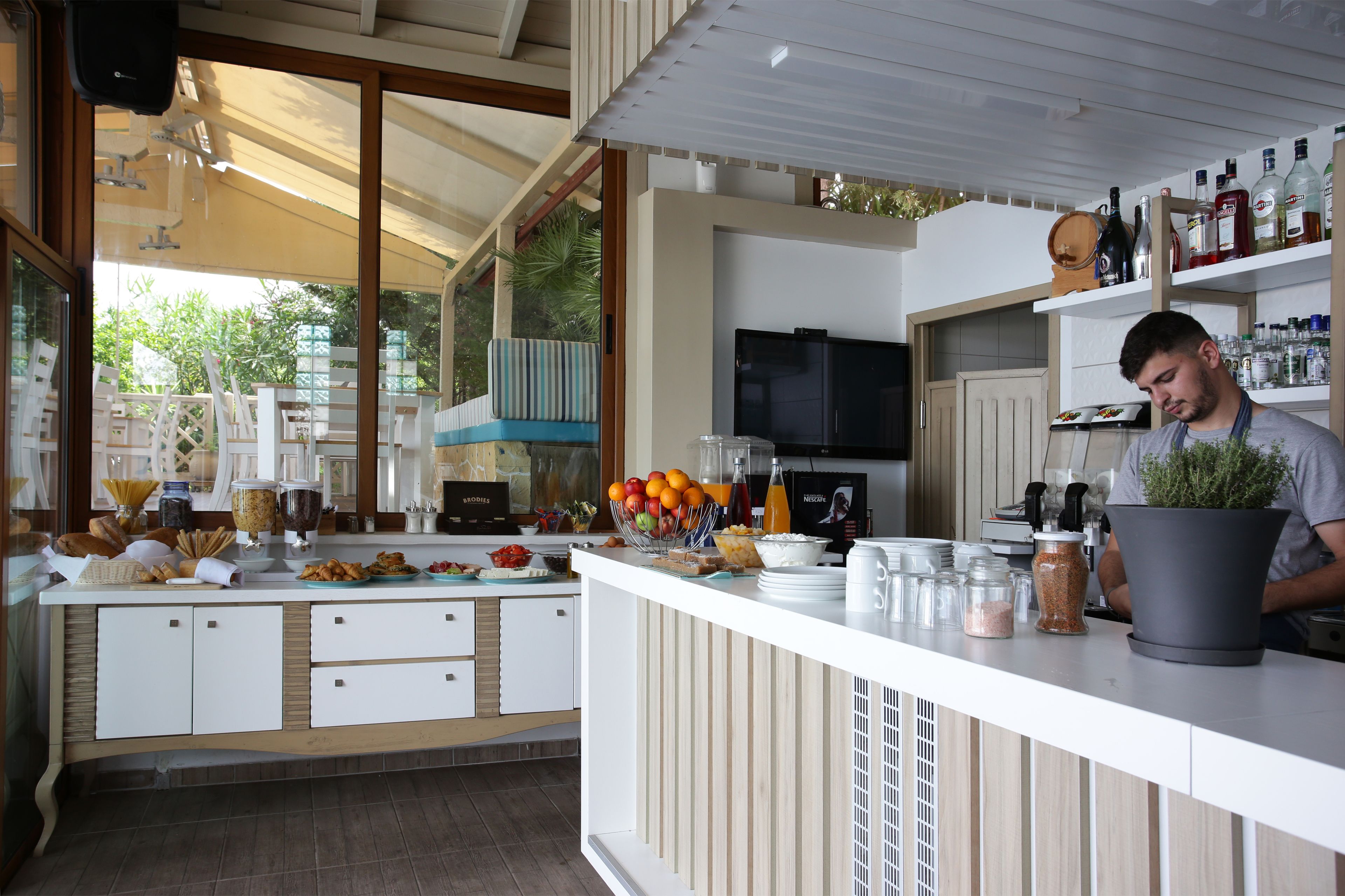 A modern kitchen with a white countertop, various food items, and a potted plant.