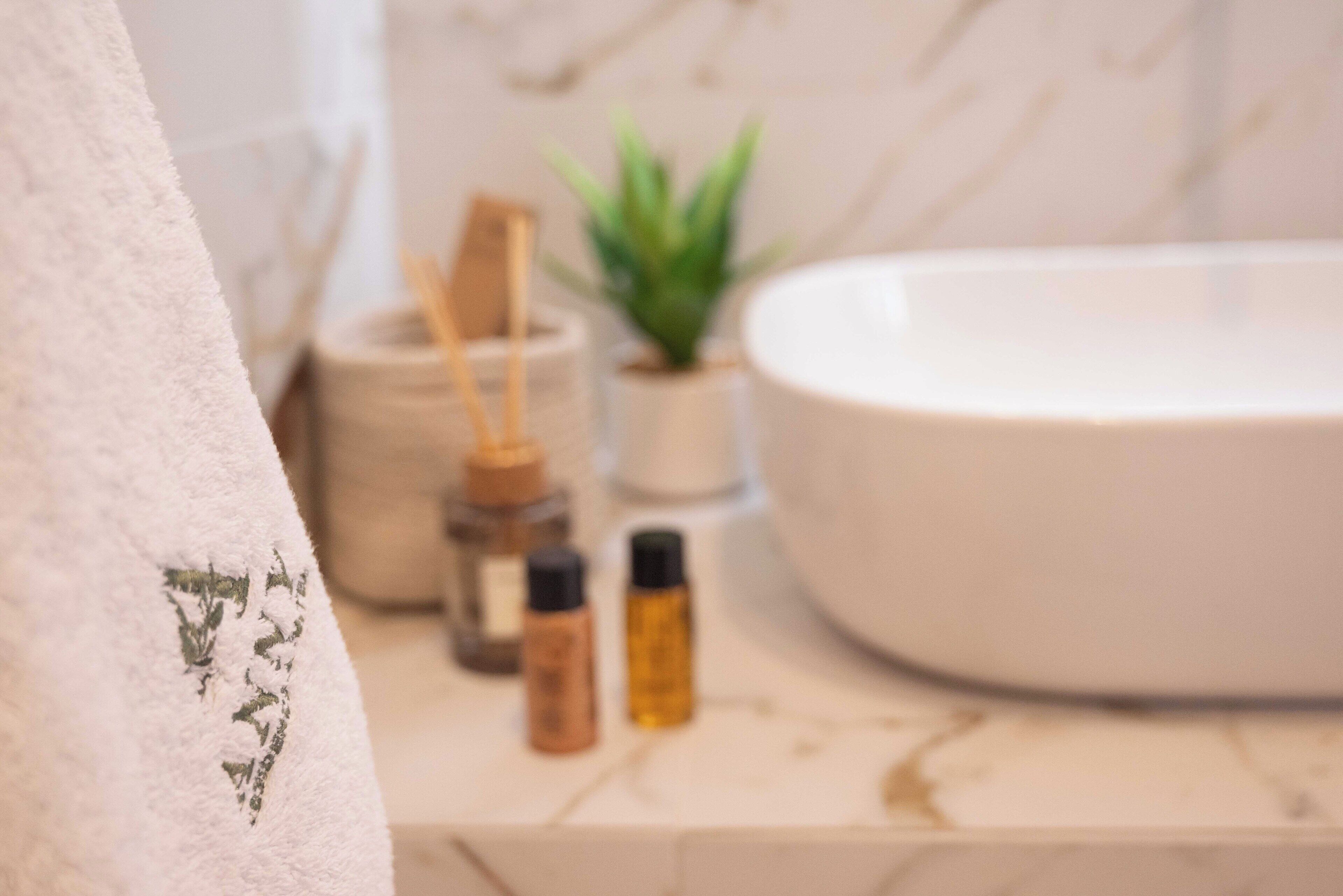 A bathroom with a white sink, a towel, and a small potted plant.