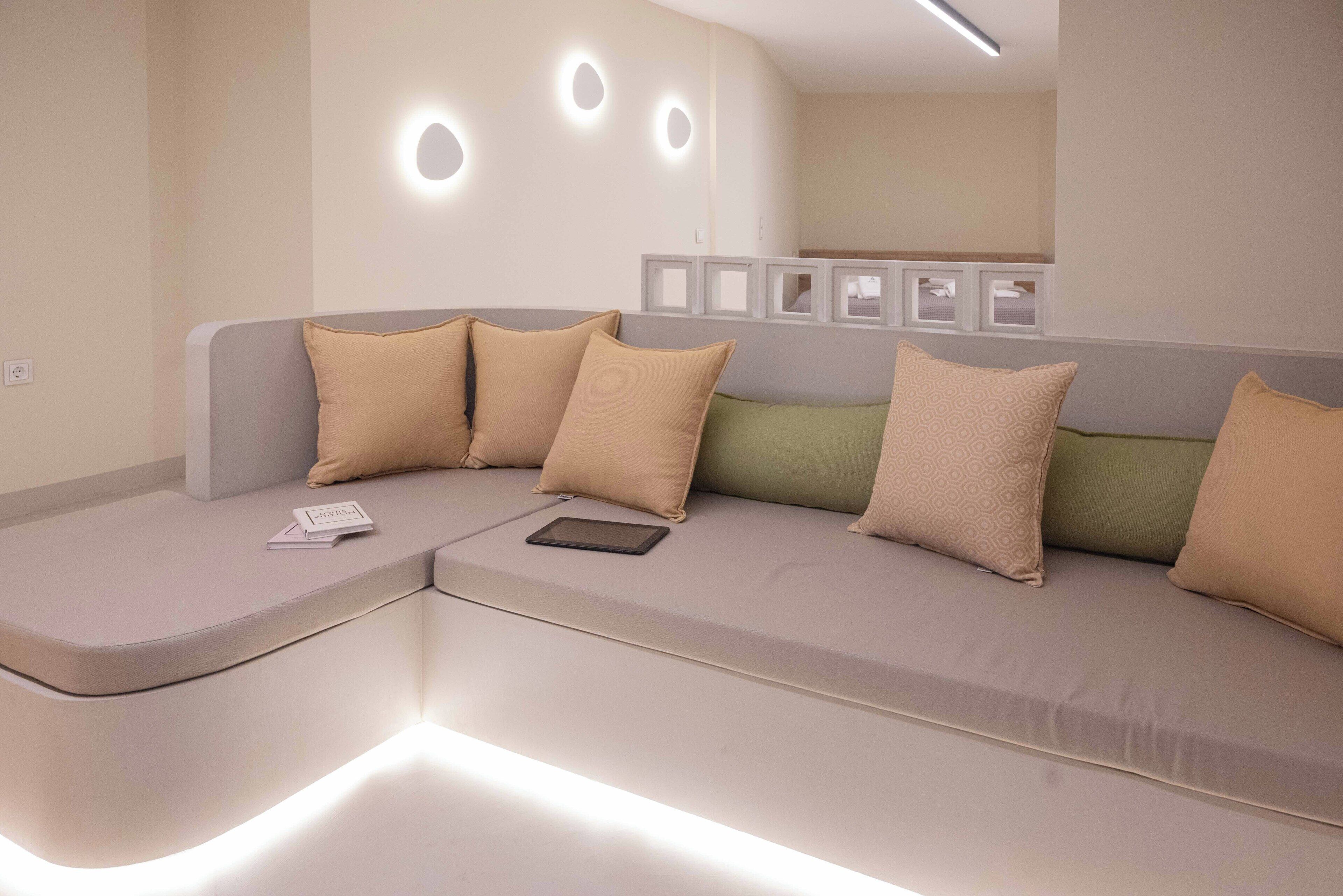 Un salon moderne et épuré, avec un canapé aux lignes courbes, de nombreux coussins et une tablette posée sur l’accoudoir.