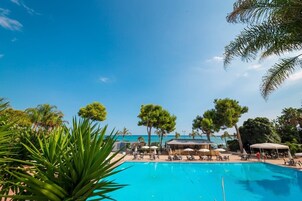 Una piscina al aire libre, sombrillas, sillones reclinables de piscina