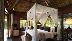 A room with a canopy bed, a sofa, a TV, and a lamp.